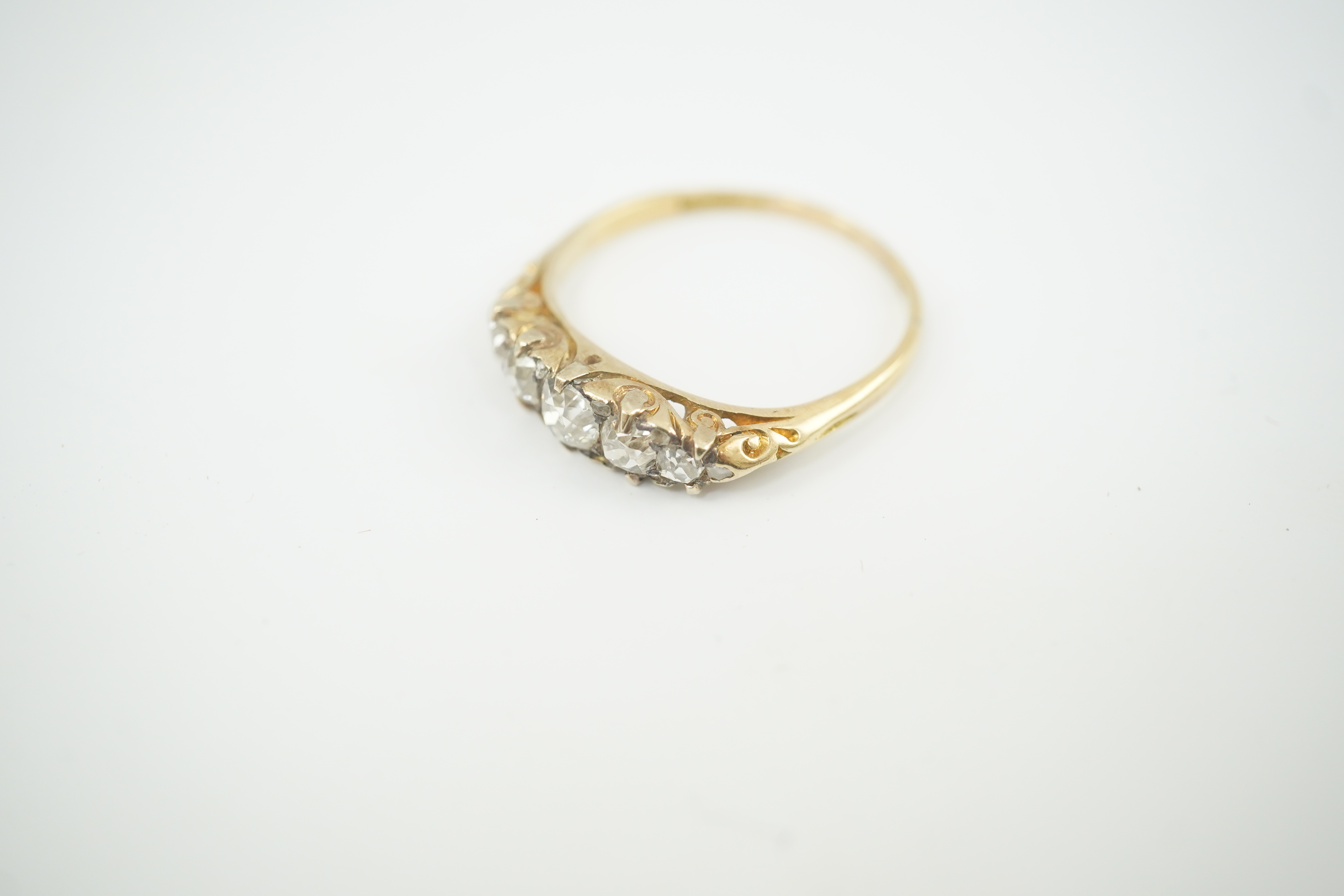 An early 20th century gold and graduated five stone old cut diamond set half hoop ring